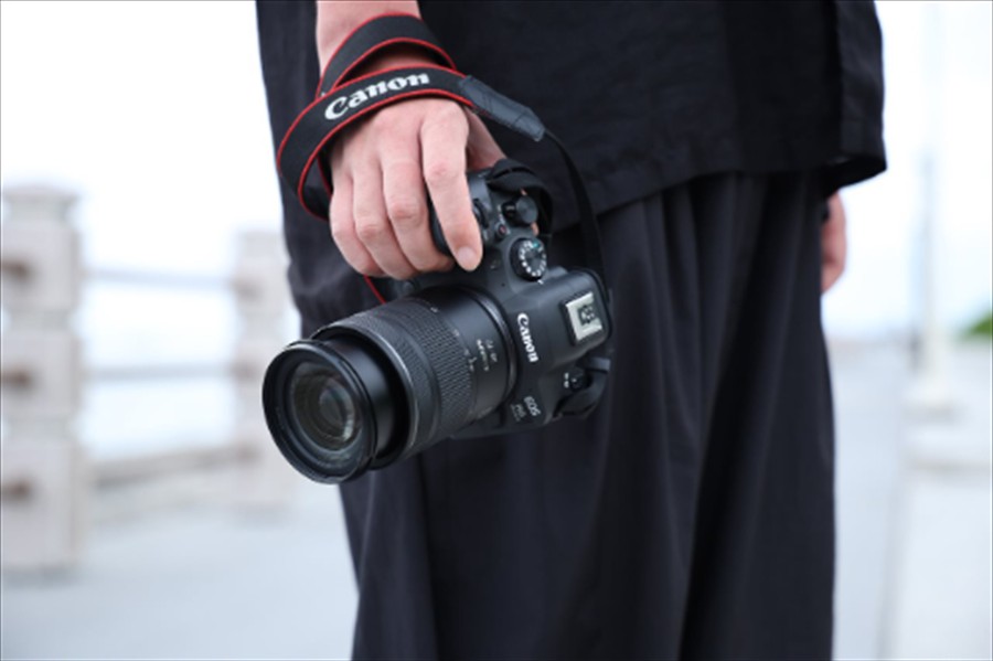 Man holding at his side a Canon RF28-70.