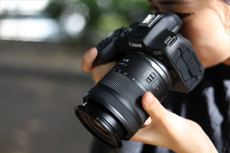Woman looking through the lens and adjusting the focus on the Canon RF-16-28.